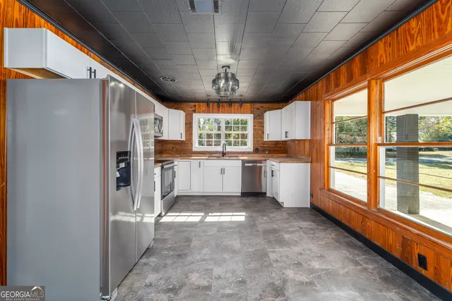 a large white kitchen with a window and refrigerator
