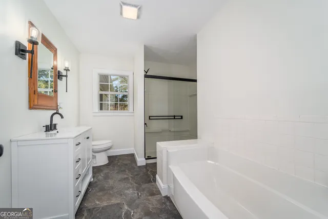 a bathroom with a tub sink toilet and a mirror