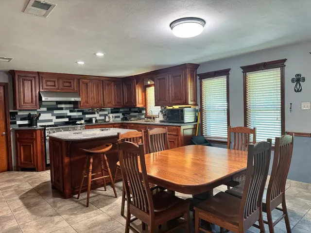 a kitchen with a dining table chairs and refrigerator