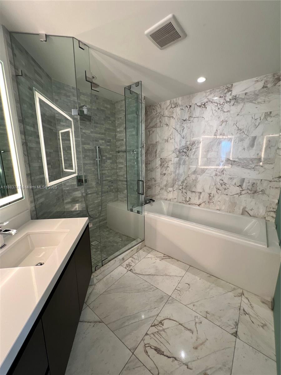 851 Northeast 1st Avenue, Unit 1208 Miami, FL 33132 - Photo 11 of 26 a bathroom with a granite countertop sink a bathtub and shower