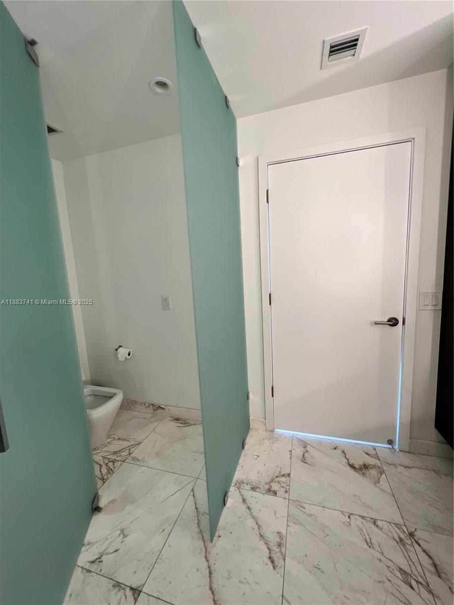 851 Northeast 1st Avenue, Unit 1208 Miami, FL 33132 - Photo 12 of 26 a bathroom with a granite countertop shower and a toilet