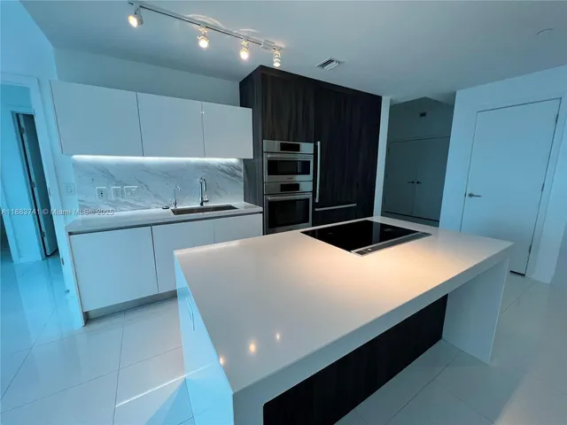 a kitchen with kitchen island sink and refrigerator