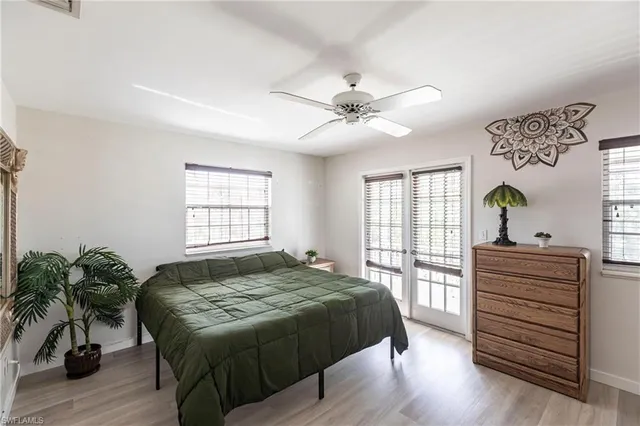 a bedroom with a bed next to a large window with wooden floor
