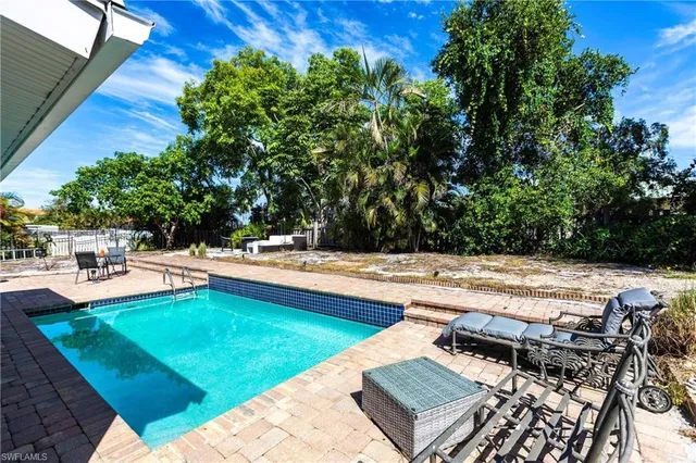 a view of backyard with swimming pool and seating space