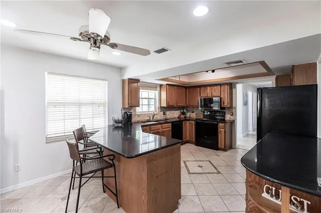 a kitchen with stainless steel appliances kitchen island granite countertop a refrigerator a stove a sink a dining table and chairs with wooden floor