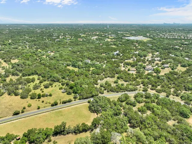 an aerial view of residential houses with outdoor space and trees