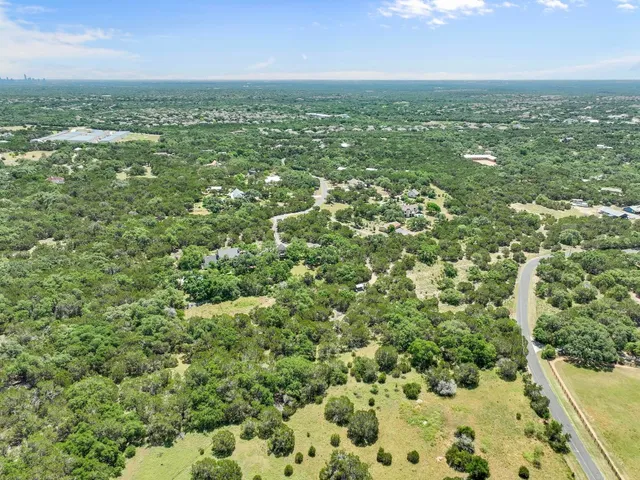 an aerial view of residential houses with outdoor space and trees