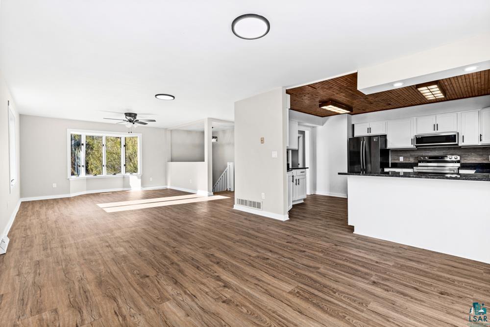 1148 Shoreview Road Two Harbors, MN 55616 - Photo 11 of 48 Kitchen with white cabinets, backsplash, stainless steel appliances, and dark wood-type flooring