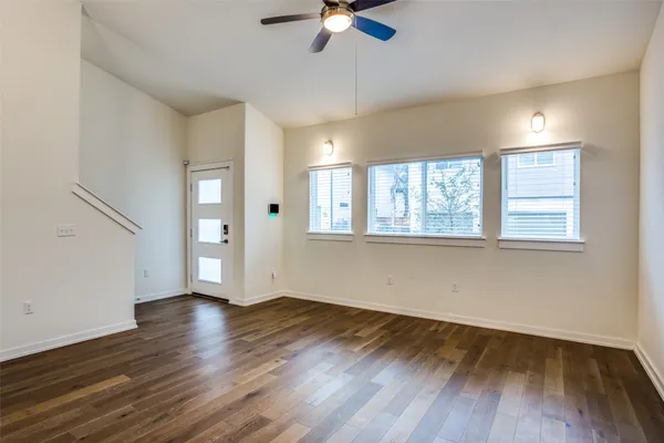 a view of an empty room with wooden floor and a window
