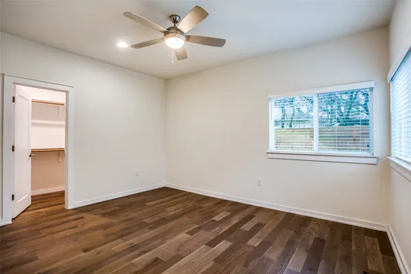 a view of empty room with wooden floor and fan