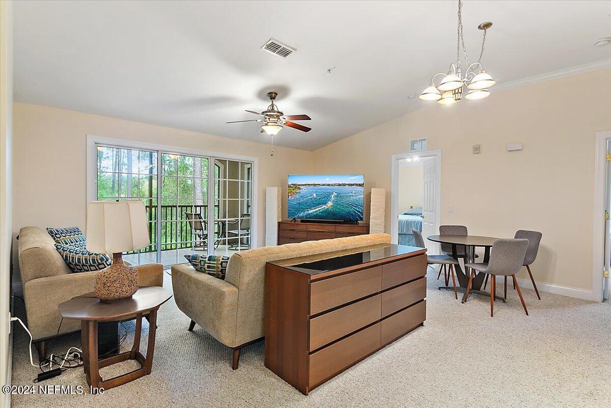160 Legendary Drive, Unit 206 St. Augustine, FL 32092 - Photo 2 of 20 a living room with furniture a chandelier and a flat screen tv