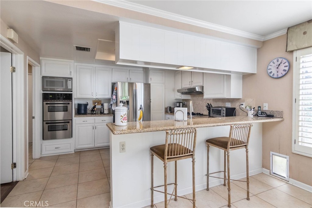 19343 Pauma Valley Drive Porter Ranch, CA 91326 - Photo 13 of 28 a kitchen with stainless steel appliances kitchen island granite countertop a refrigerator and cabinets