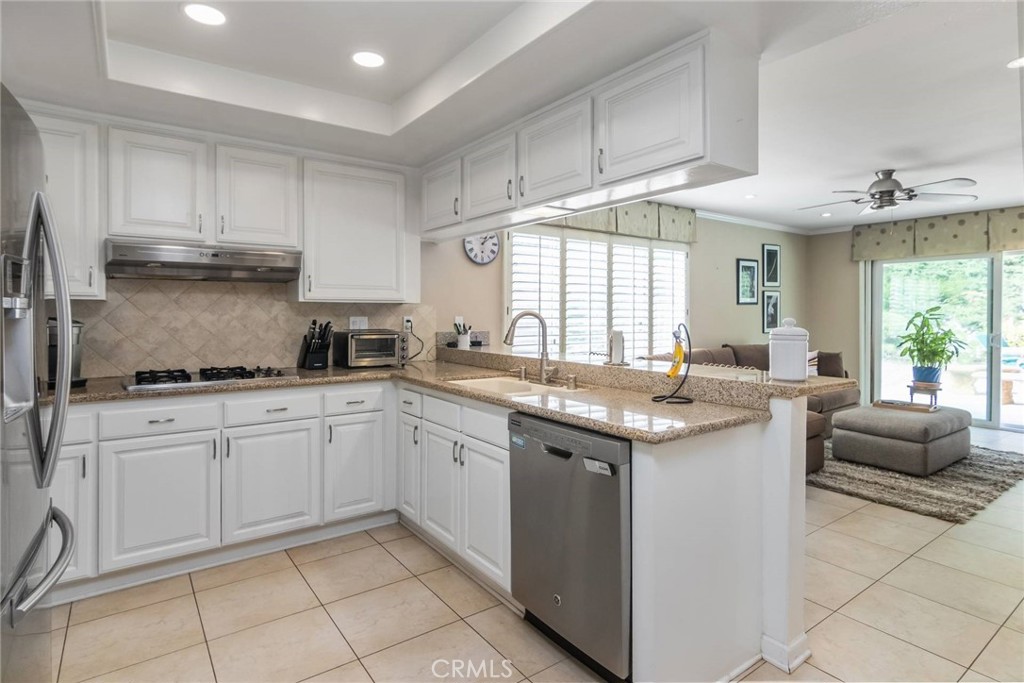 19343 Pauma Valley Drive Porter Ranch, CA 91326 - Photo 15 of 28 a kitchen with granite countertop a sink and dishwasher a stove top oven with white cabinets