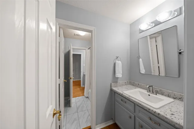 a en suite bathroom with a granite countertop sink and a mirror