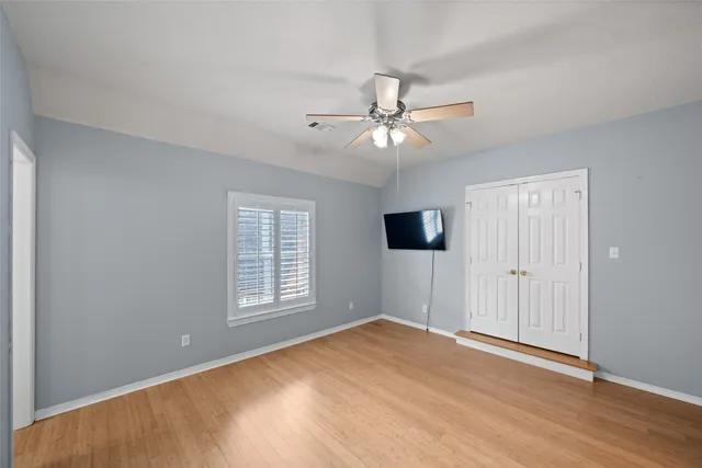 a view of empty room with wooden floor and fan