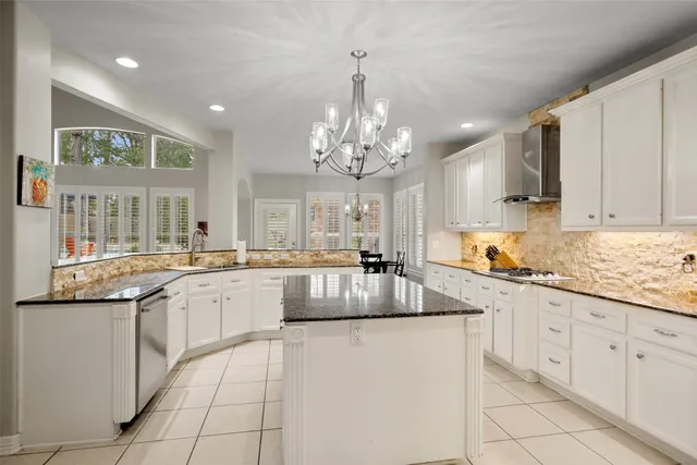 a kitchen with stainless steel appliances granite countertop a sink and dishwasher a stove with white cabinets
