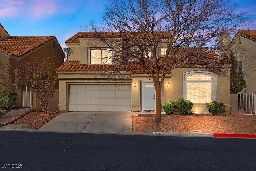 View of front of home with a tile roof, a garage,