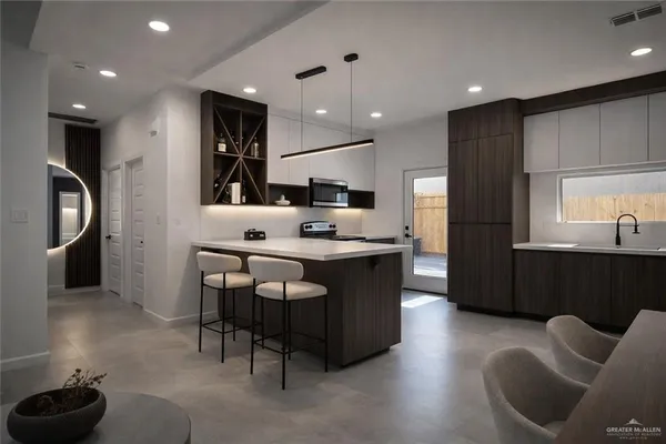 a kitchen with stainless steel appliances kitchen island granite countertop a refrigerator a sink a stove and a microwave