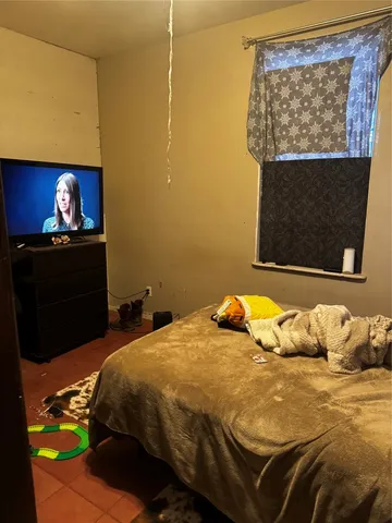 a bedroom with a bed a dresser and painting on the wall