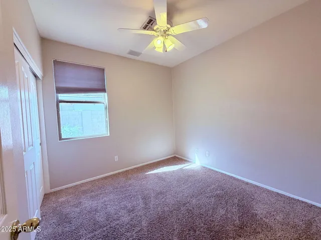 an empty room with a window and a fan