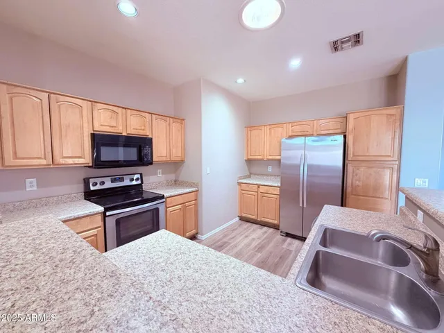 a kitchen with granite countertop a stove refrigerator and microwave
