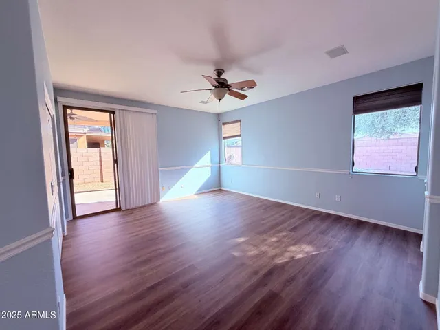 an empty room with wooden floor chandelier fan and windows
