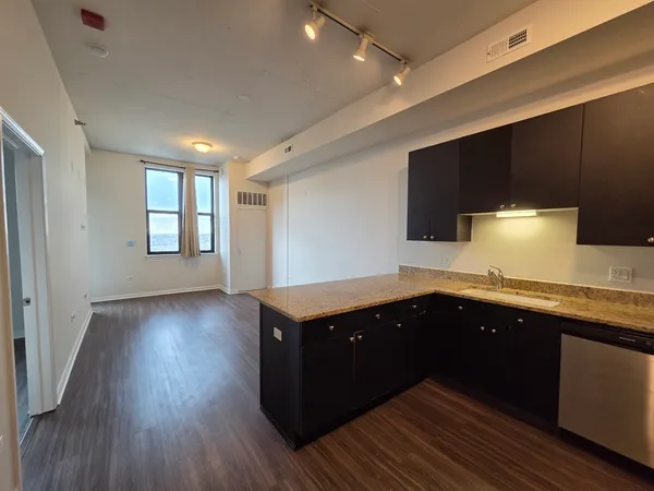 a kitchen with kitchen island granite countertop a refrigerator and a sink