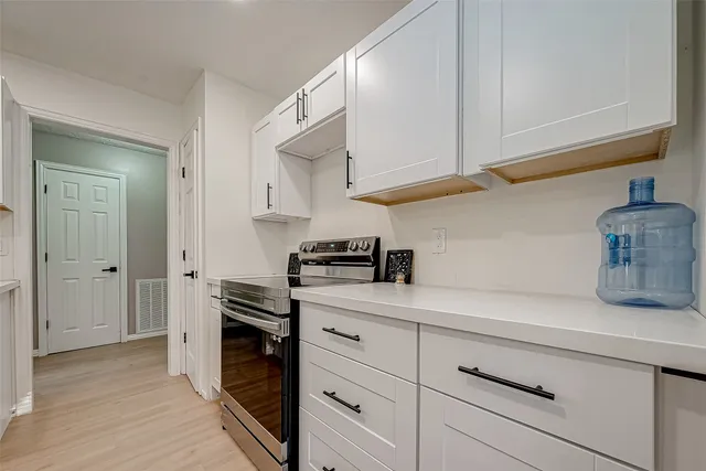 a kitchen with stainless steel appliances white cabinets and a wooden floor