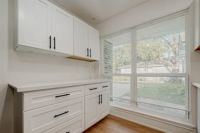 a kitchen with white cabinets and a wooden floor