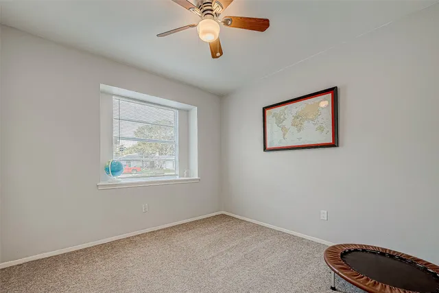 a view of an empty room with window and a fan