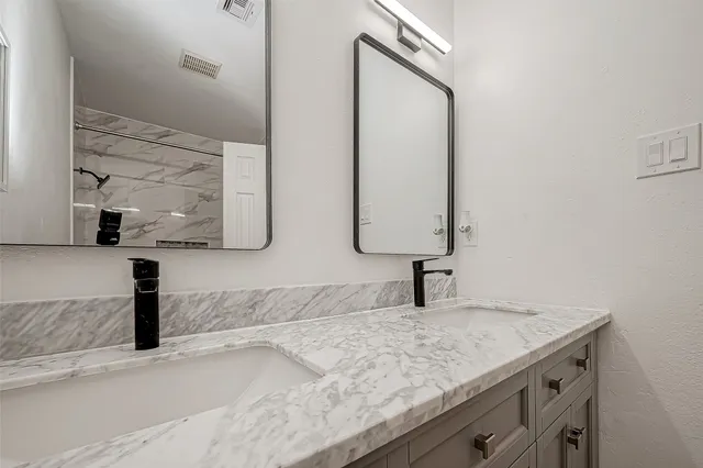 a bathroom with a granite countertop sink and a mirror
