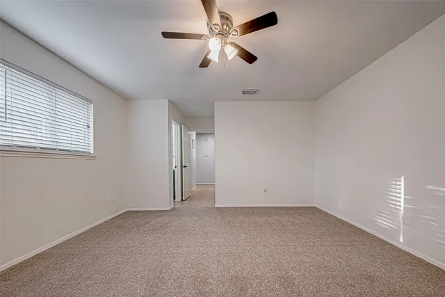 an empty room with a window and a fan