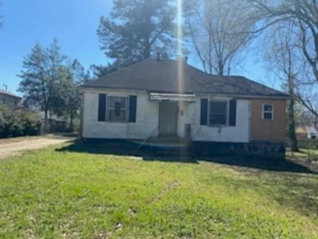 a front view of house with yard and trees in the background