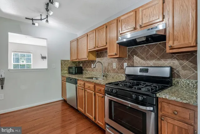 a kitchen with granite countertop wooden cabinets and a stove top oven
