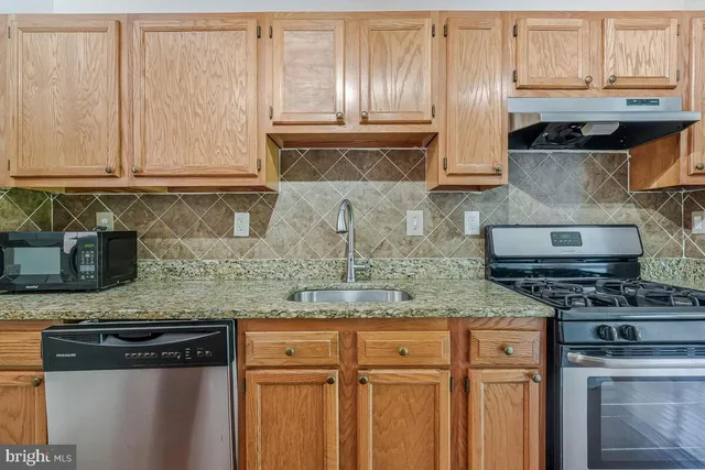 a kitchen with granite countertop a sink a stove and cabinets