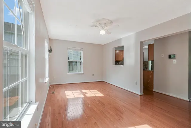 a view of an empty room with wooden floor and a window