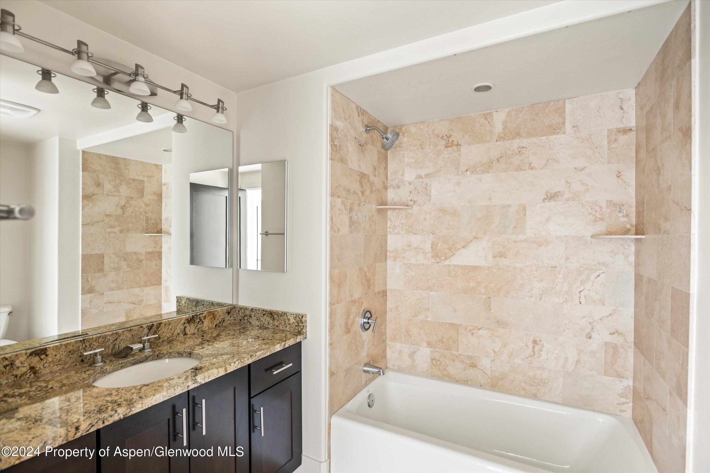 450 Jody Road Basalt, CO 81621 - Photo 16 of 22 a bathroom with a granite countertop sink a mirror a bathtub and shower