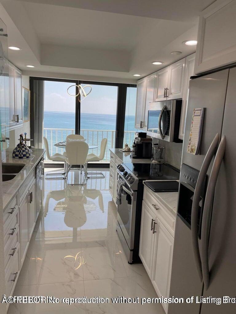 3360 South Ocean Boulevard, Unit 6CII Palm Beach, FL 33480 - Photo 5 of 12 a kitchen with stainless steel appliances a stove a sink dishwasher a refrigerator white cabinets with wooden floor