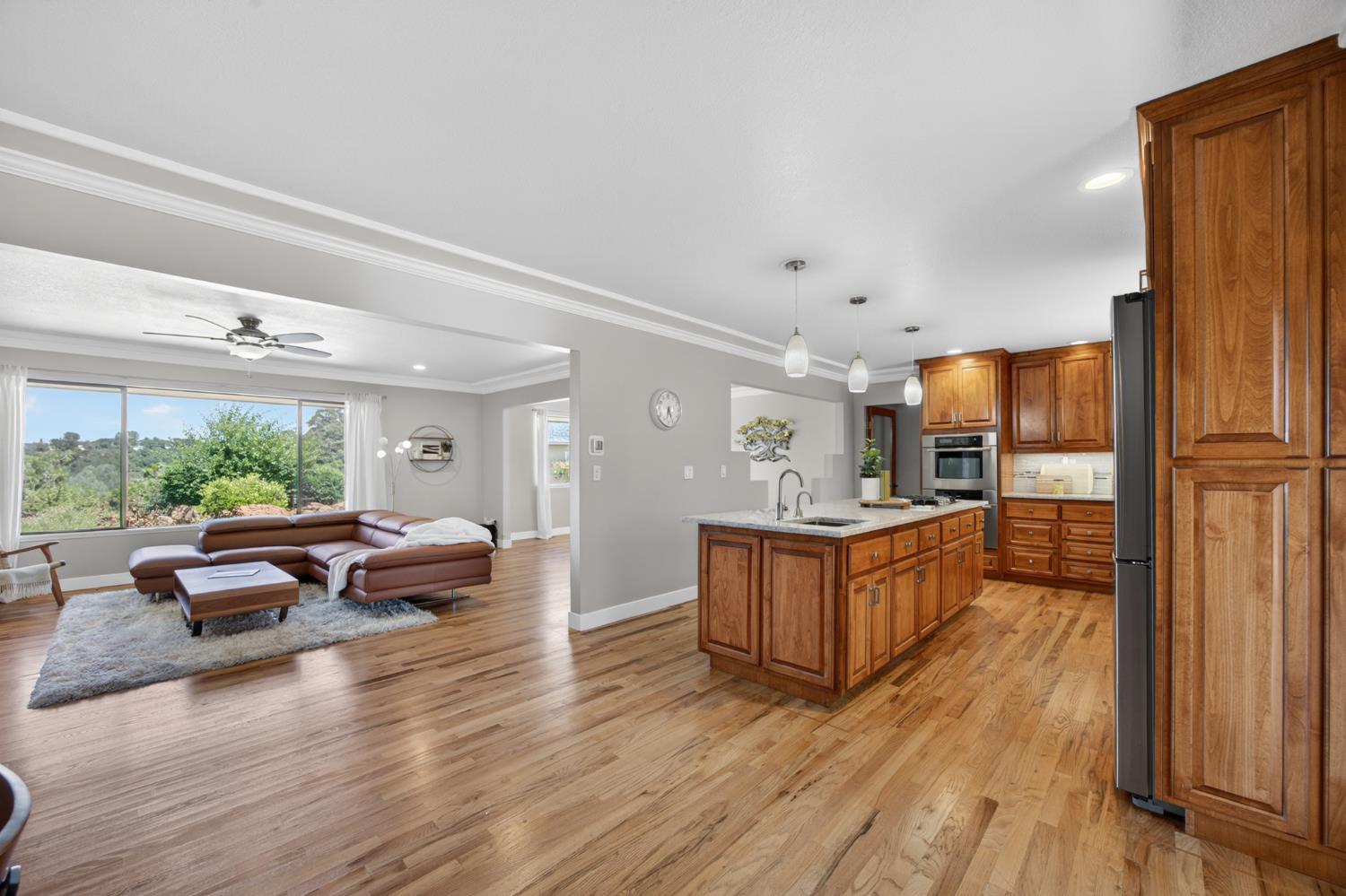 5560 Ralston Way Placerville, CA 95667 - Photo 17 of 78 Expansive kitchen and living area featuring wood flooring, a kitchen island with pendant lighting, wood cabinetry, built-in oven, and large windows