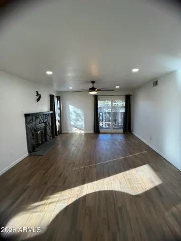 an empty room with wooden floor fireplace and windows
