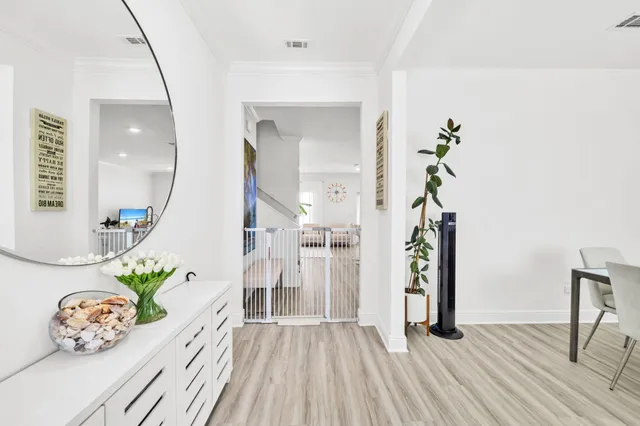 a kitchen with stainless steel appliances a sink dishwasher a stove top oven a refrigerator with white cabinets and wooden floor