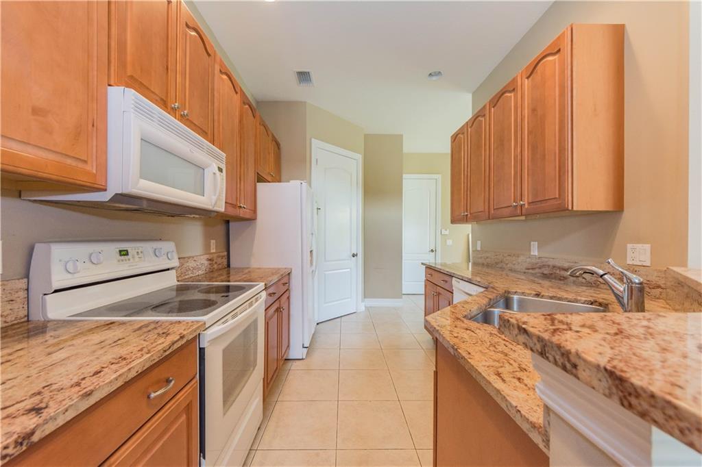 1855 Bridgepointe Circle, Unit 21 Vero Beach, FL 32967 - Photo 7 of 35 a kitchen with granite countertop a sink a stove and cabinets
