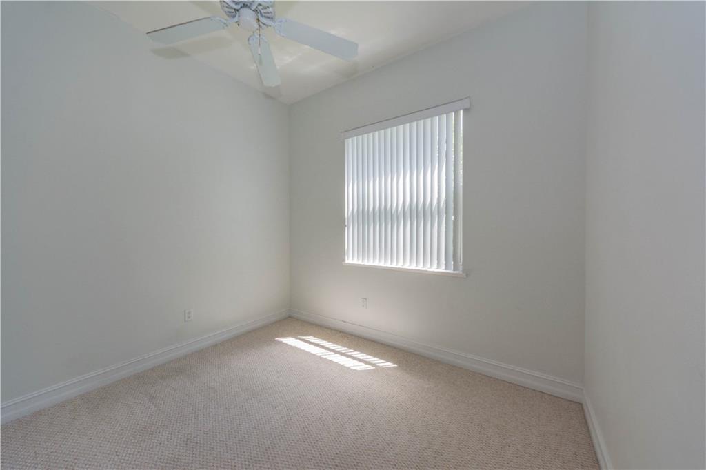 1855 Bridgepointe Circle, Unit 21 Vero Beach, FL 32967 - Photo 9 of 35 an empty room with a chandelier fan and windows