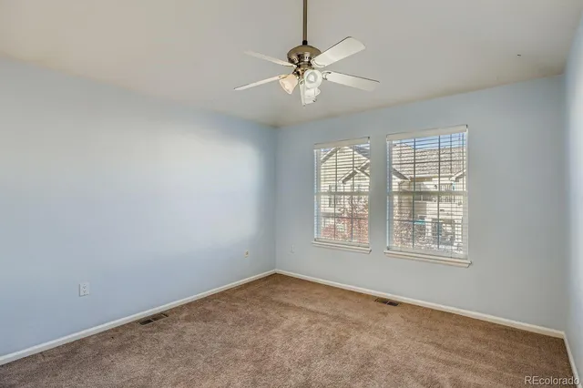 an empty room with windows and fan