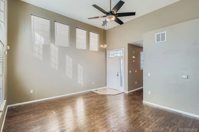 an empty room with wooden floor fan and windows