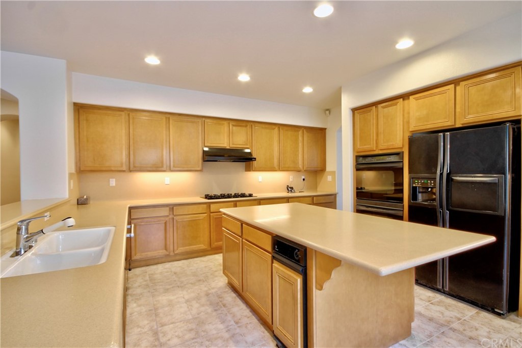 30099 Corte Coelho Temecula, CA 92591 - Photo 18 of 47 a large kitchen with stainless steel appliances kitchen island a stove a sink a refrigerator and a dining table with wooden cabinet