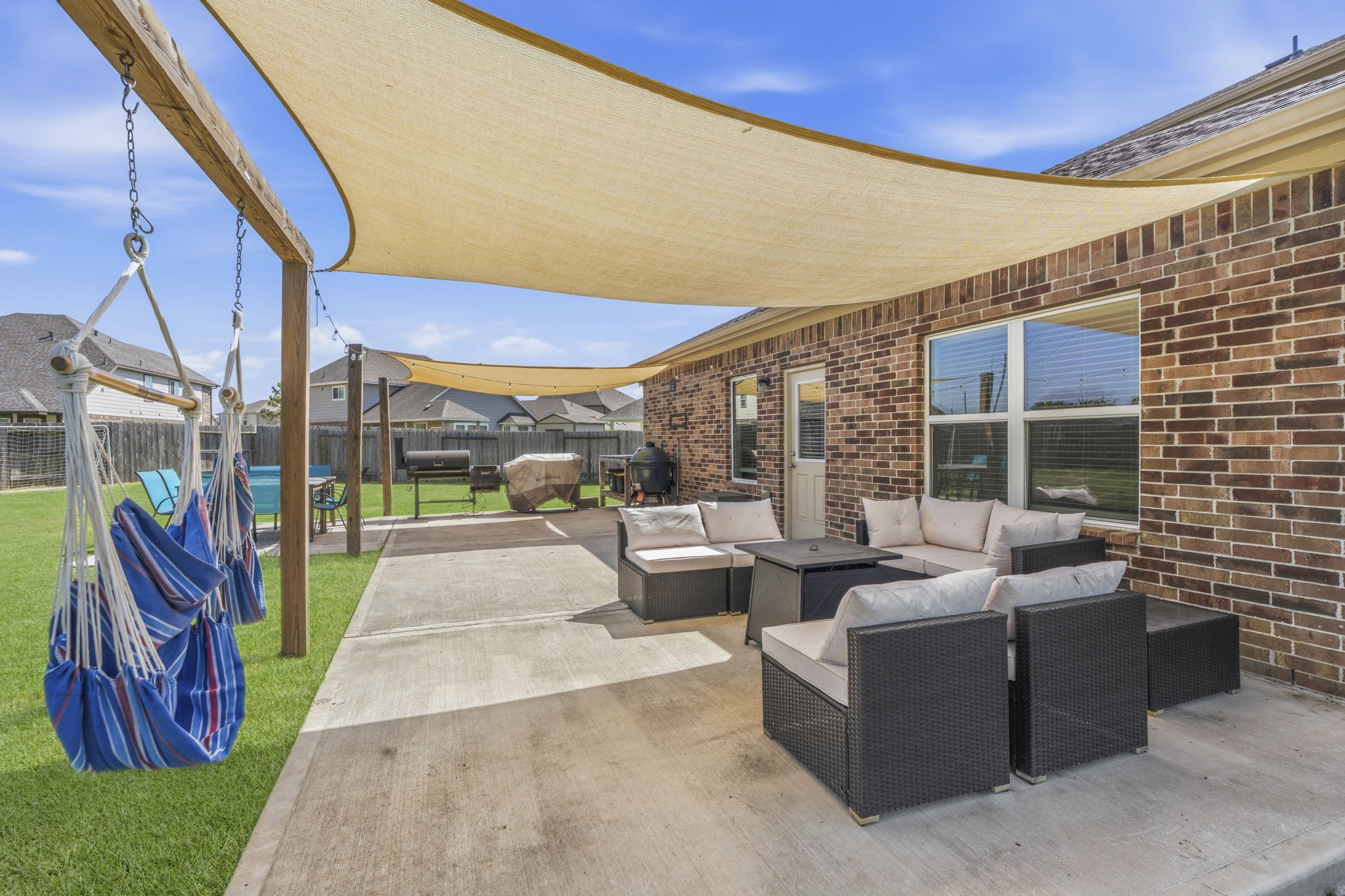 2401 Abbot Brk Drive Rosharon, TX 77583 - Photo 36 of 50 Designed for outdoor living and entertaining, this backyard retreat features a 12' x 23' patio spanning the length of the home, plus an additional 11' x 10' open-air extension. Two inviting gathering areas are shaded with canopies and enhanced by charming string lights for evening ambiance. With space for lounging, dining, and grilling, this outdoor setting is perfect for relaxing and entertaining while enjoying peaceful greenbelt views.