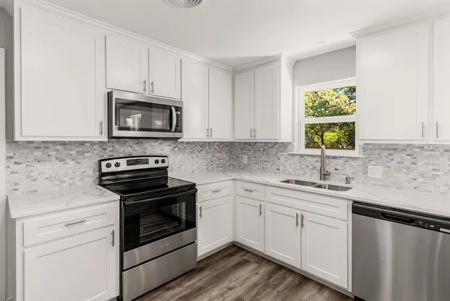 a kitchen with cabinets stainless steel appliances a sink and a window