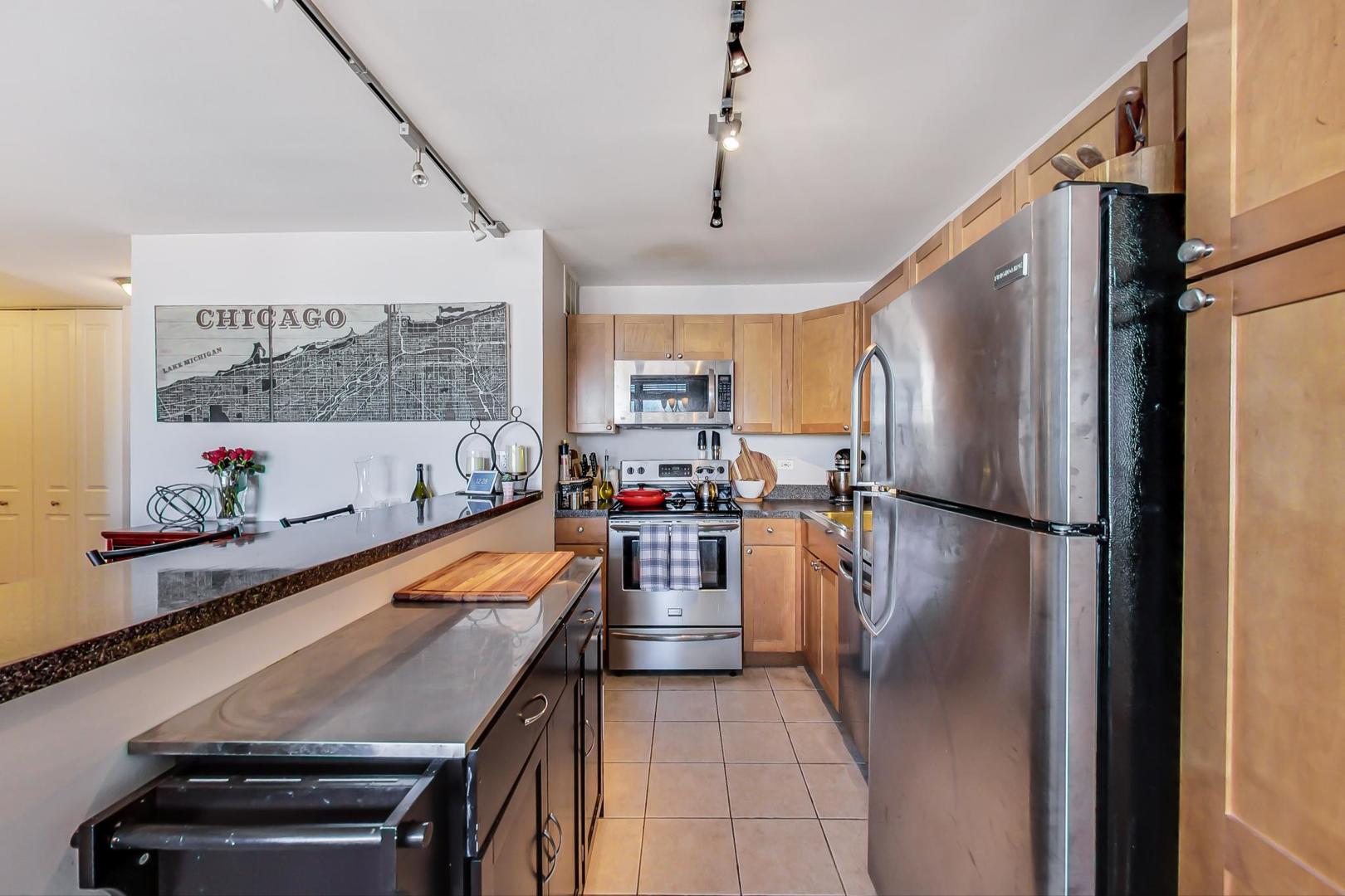 655 West Irving Park Road, Unit 2108 Chicago, IL 60613 - Photo 14 of 34 a kitchen with stainless steel appliances granite countertop a refrigerator a sink dishwasher a stove and a dining table with wooden floor