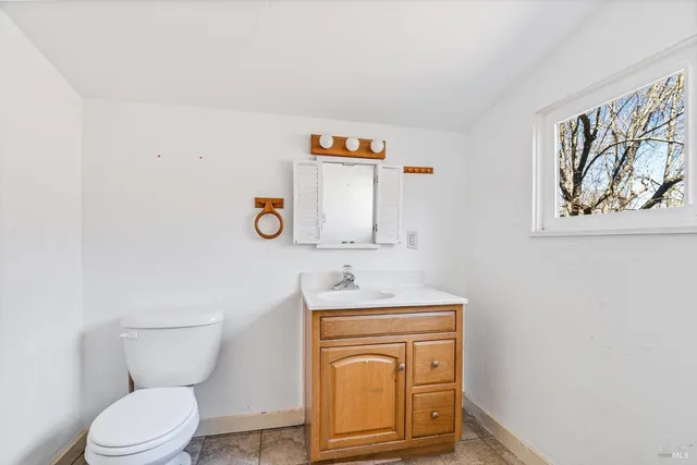 a bathroom with a toilet sink vanity and mirror
